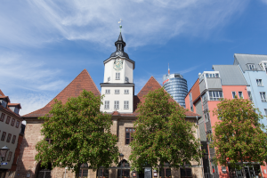 Blick auf das historische Rathaus vom Marktplatz aus, rechts daneben mehrere farbige Gebäude, im Hintergrund der Jentower