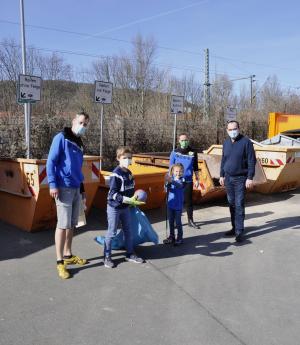 Drei Erwachsenen und zwei Kinder ahebn Mülltüten in der Hand