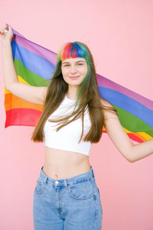 Eine Frau mit gefärbten Haaren hält eine Regenbogenfahne