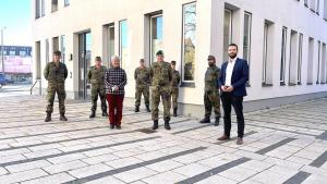 Mehrere Personen stehen im Außenbereich vor einem Gebäude. Einige tragen zivile Kleidung, einige tragen Bundeswehr-Uniform.