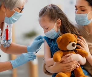 Ein Kind mit Teddy lässt sich impfen