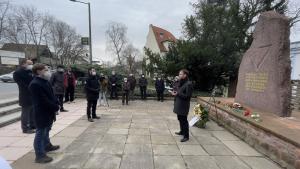 Menschen stehen vor einem Gedenkstein, ein Redner im Vordergrund