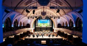 Blick in das Volksbad die Wände sind blau angeleuchtet in der Mitte die Bühne mit den Musiker:innen der Jenaer Philharmonie