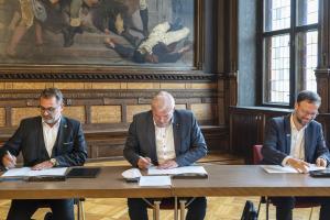 Die Oberbürgermeister von Erfurt, Jena und Gera sitzen an einem Tisch und unterzeichnen einen Vertrag. 