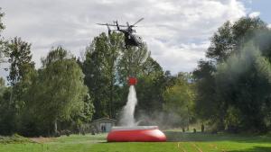 Ein Hubschrauber entlädt sehr viel Wasser in einen Behälter