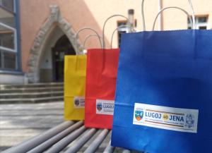 Drei Geschenketüten für die Gäste aus Lugoj stehen vor dem Gebäude Anger 15 auf einer Bank.:
