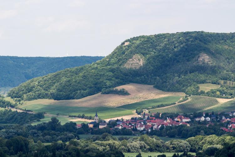 Ein Dorf mit einer Kirche im Hintergrund ein hoher Berg mit einer Burgruine