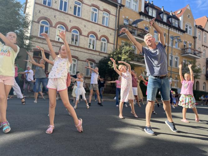 Gruppenbild von tanzenden Kindern auf der abgesperrten Straße im Damenviertel
