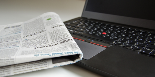 Eine zusammengefaltete Zeitung und ein Laptop auf einem Tisch