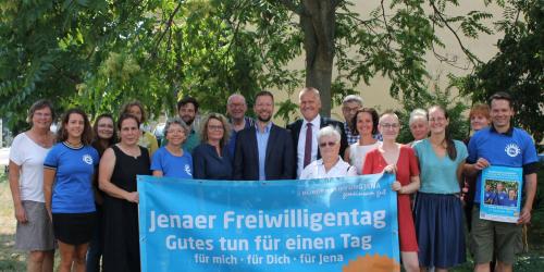 OB Nitzsche, Jenapharm-Geschäftsführer Gerber, zahlreiche Einsatzstellen und die Mitarbeiter der Freiwilligenagentur und Bürgerstiftung Jena halten ein Banner des Freiwilligentags.