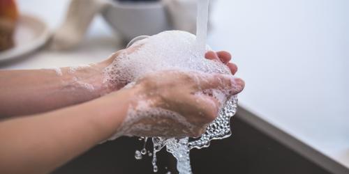 Eine Person wäscht sich seine Hände unter fleißendem Wasser, es schäumt