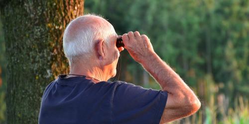 Ein Senior schaut durch ein Fernglas in die Weite