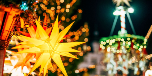 Ein beleuchteter Weihnachtsstern, im Hintergrund Marktgetümmel