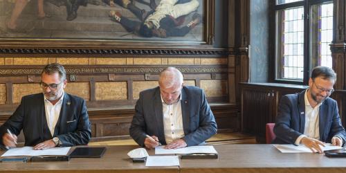 Die Oberbürgermeister von Erfurt, Jena und Gera sitzen an einem Tisch und unterzeichnen einen Vertrag. 
