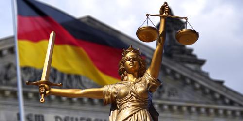 Eine Figur, die Jura symbolisiert vor der deutschen Flagge