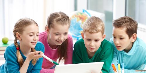 4 Kinder schauen auf einen Lapto-Bildschirm.