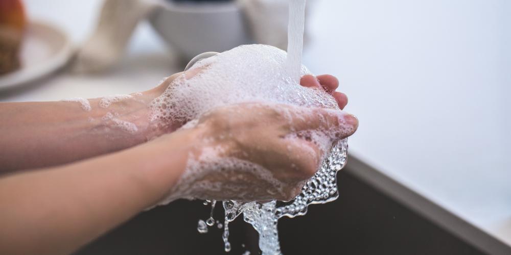 Eine Person wäscht sich seine Hände unter fleißendem Wasser, es schäumt