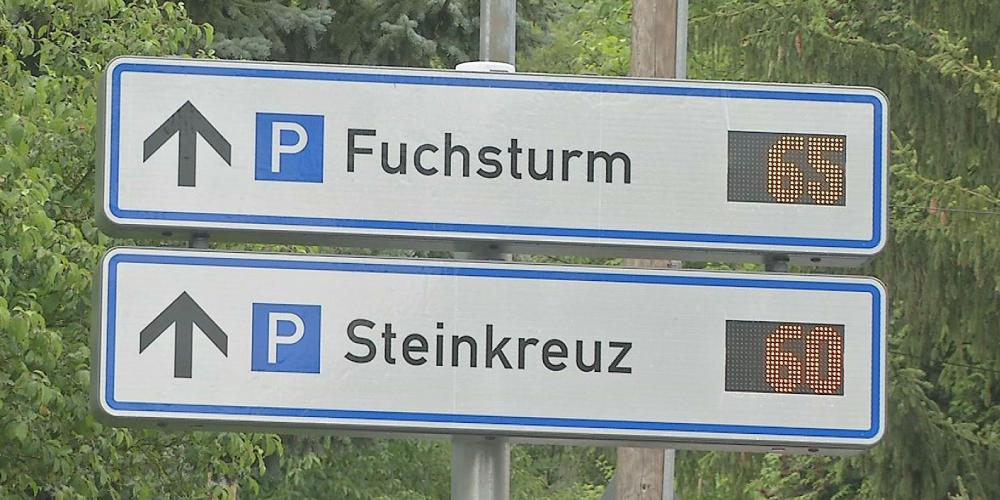 Zwei rechteckige weiße Schilder mit der Aufschrift Fuchsturm und Steinkreuz. Dahinter befindet sich die Digitalanzeige mit der Anzahl der freien Parkplätze.