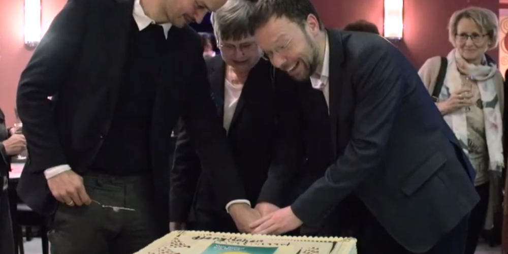 Drei Menschen schneiden eine Torte an