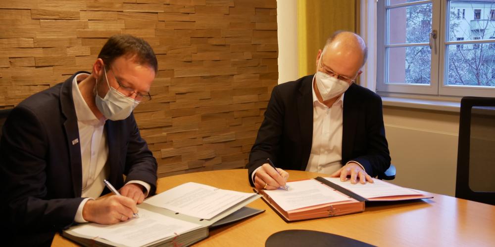 Dr. Thomas Nitzsche und Tobias Wolfrum unterzeichnen den Kooperationsvertrag zur Unterbringung von Geflüchteten.