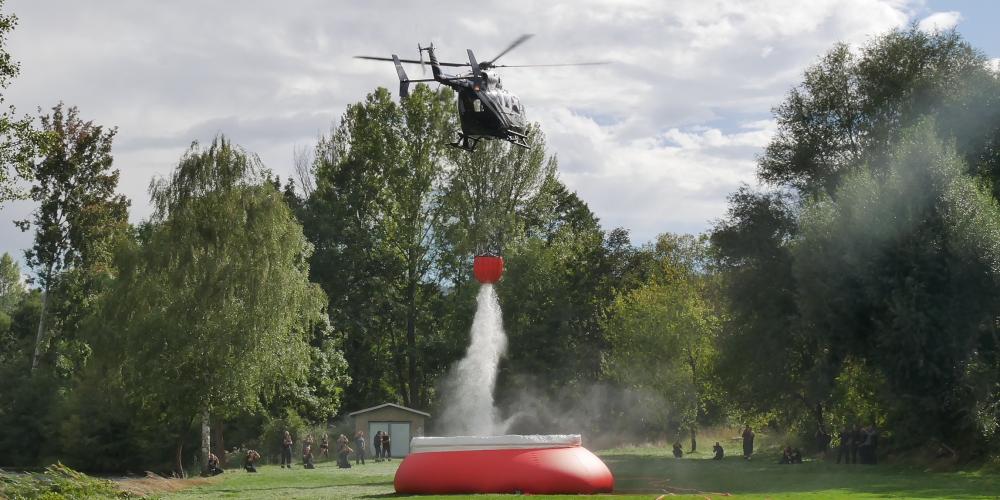 Ein Hubschrauber entlädt sehr viel Wasser in einen Behälter