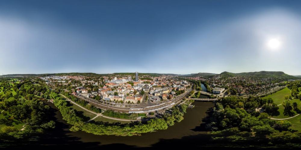 Panoramaaufnahme der Stadt Jena mit viel Grün, einem Fluss und vielen Gebäuden