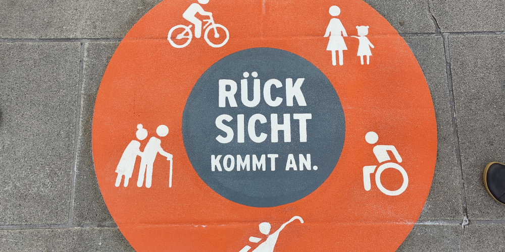 Bordenmarkierung: Orangerkreis mit weißen Symbolen (Rollstuhlfahrer, Senioren, Mutter mit Kind, KInderwagen, Radfahrer) in der Mitte steht "Rücksicht kommt an"