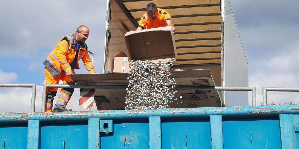 KSJ-Mitarbeiter schütten die abgeholten Kronkorken in einen Container.