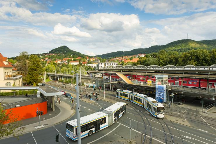 Eine Straße mit einem Bus und einer Straßenbahn, im Hintergrund ein Zug