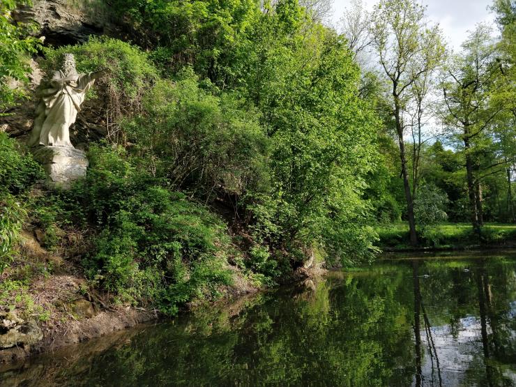 Auf einem Hang an einem Teich steht eine Statue.