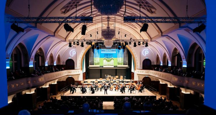 Blick in das Volksbad die Wände sind blau angeleuchtet in der Mitte die Bühne mit den Musiker:innen der Jenaer Philharmonie