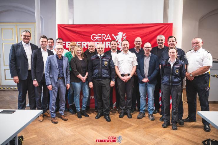 Eine Gruppe von Menschen steht nebeneinander und lacht in die Kamera