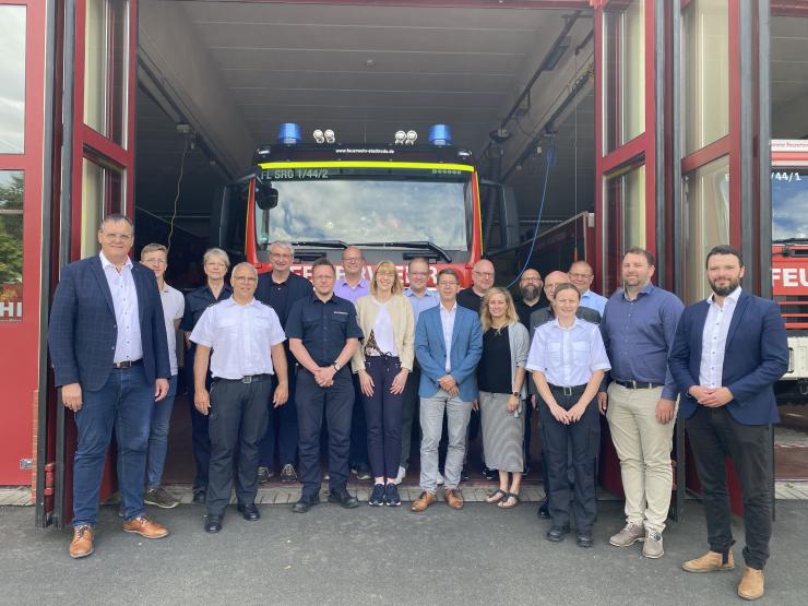 Viele Menschen stehen vor einer Feuerwache und schauen in die Kamera.