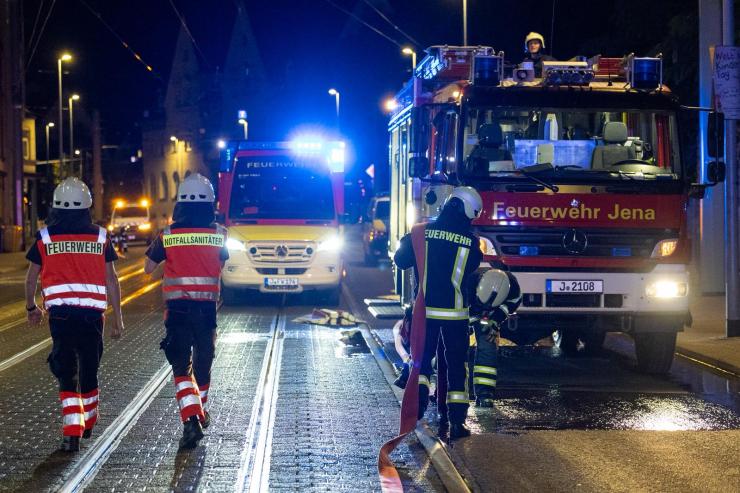 Feuerwehrmänner vor Feuerwehrautos während des Einsatzgeschehens