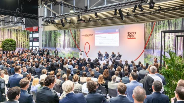 Viele Menschen sitzen im Publikum und hören Podiumsdiskussion zu.