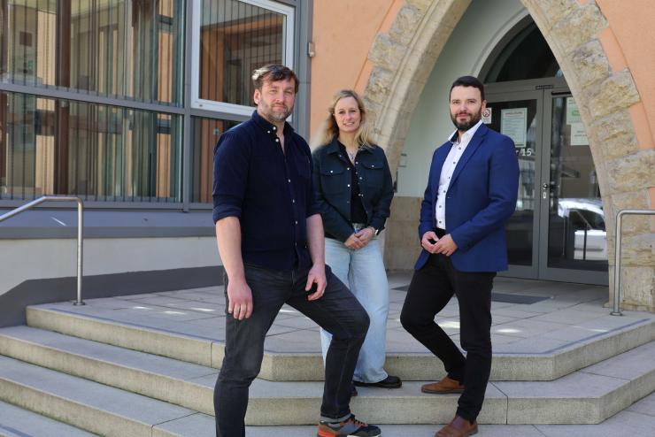 Drei Personen lächeln in die Kamera.