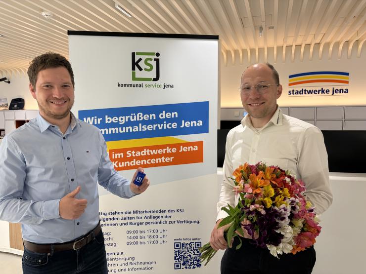 Zwei Männer stehen nebeneinander. Der eine hat einen Blumenstrauß in der Hand.