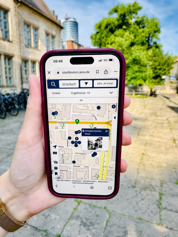 Hand hält Smartphone, auf dem eine Stadtkarte zu sehen ist. 