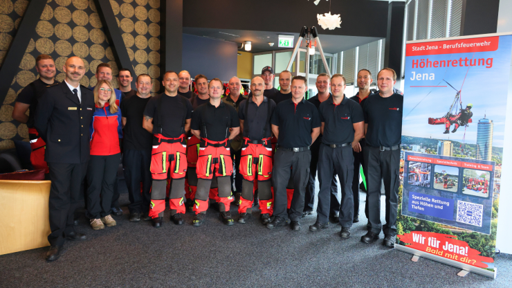 Gruppe von Menschen stehen im JenTower und lachen in die Kamera.