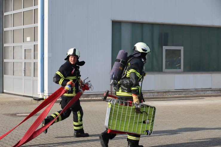 Zwei Feuerwehrmänner mit Schlauch und Equipement.