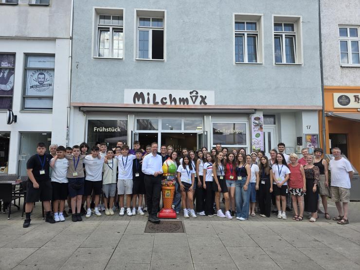 Kinder und Erwachsene stehen vor dem Eiscafé Milchmix als Gruppe zusammen