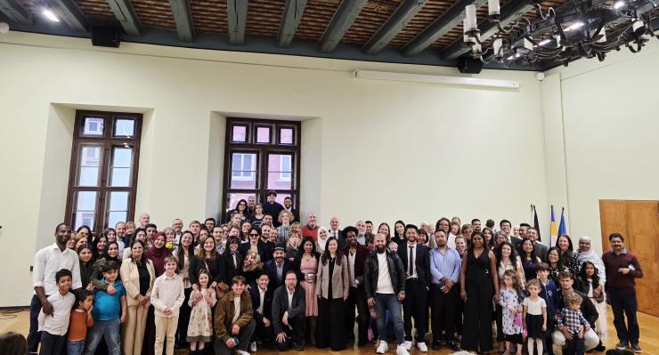 eine Gruppe von Menschen steht vor einer Wand mit zwei Fenstern und feiert ihre Einbürgerung im historischen Rathaus