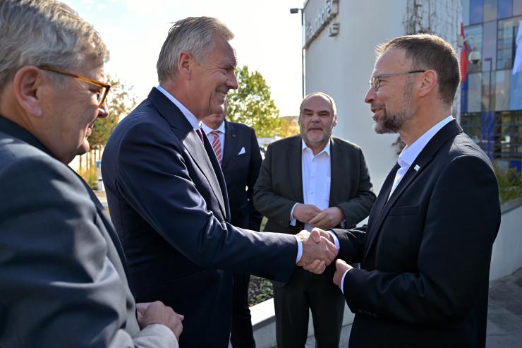 Zwei Männer geben sich die Hand und begrüßen sich, zwei weitere Männer stehen daneben