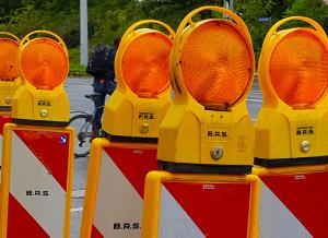 Warnbalken an einer Baustelle, im Hintergrund ein Fahrradfahrer