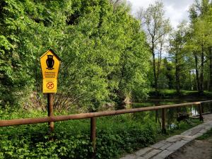 Vor einem Teich steht ein Schild. Auf dem Schild ist eine Eule abgebildet. "Geschützter Landschaftsbestandteil" ist zu lesen.