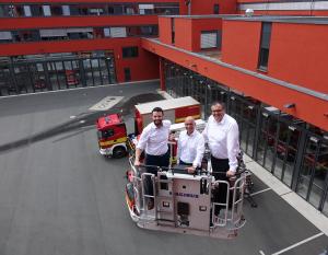 Die Dezernenten Koppe, Horn und Dannenberg (v.l.) stehen in einem Beöfrderungskorb einer Drehleiter. Die Drehleiter ist ausgefahren. Das GAZ und Feuerwehrautos sind im Hintergrund zu sehen. 