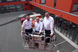 Die Dezernenten Koppe, Horn und Dannenberg (v.l.) stehen in einem Beöfrderungskorb einer Drehleiter. Die Drehleiter ist ausgefahren. Das GAZ und Feuerwehrautos sind im Hintergrund zu sehen. 