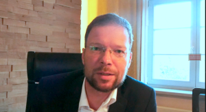 Ein Mann am Schreibtisch schaut in die Kamera