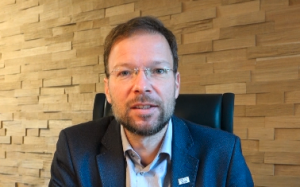 Ein Mann am Schreibtisch schaut in die Kamera