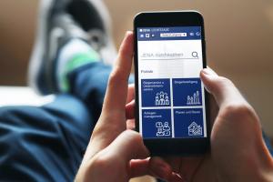 Person surft mit mobilem Endgerät im Netz